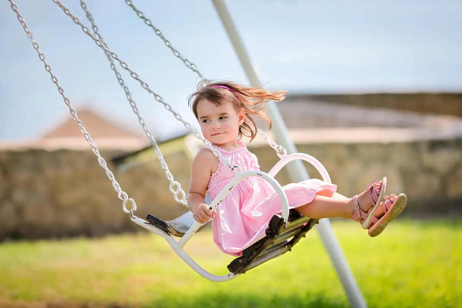 a girl in a pink dress on a swing