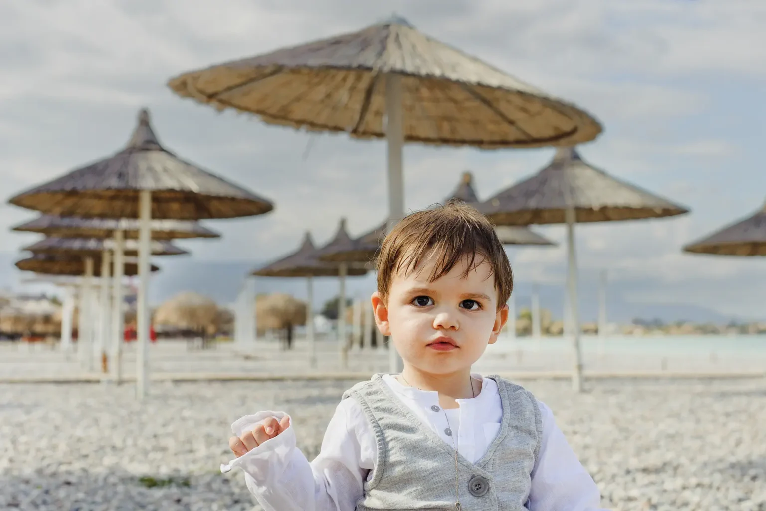 a child sitting on a beach with umbrellas