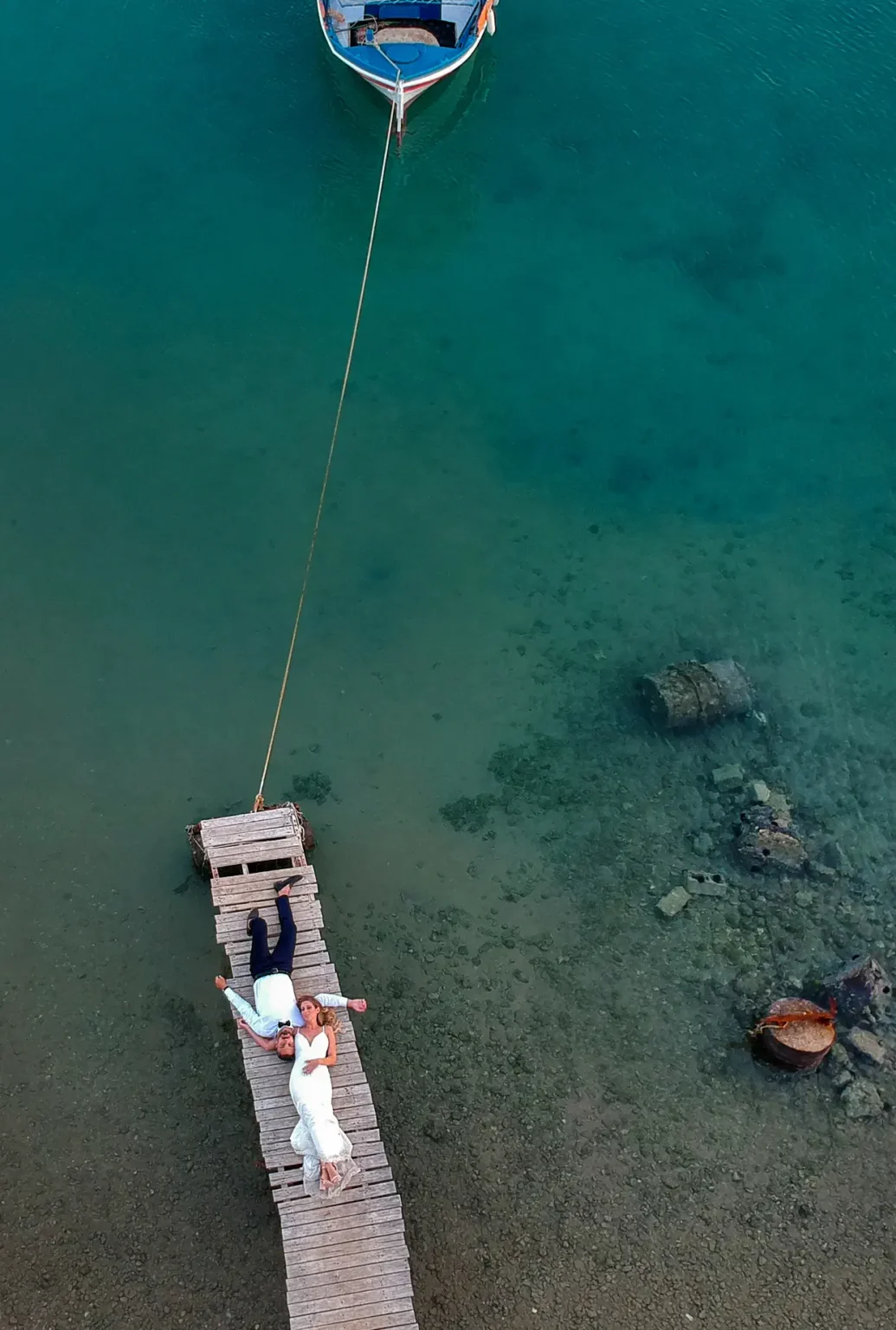 a man and woman lying on a dock in water